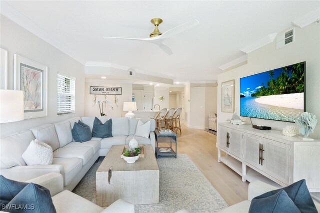 living room featuring crown molding, light hardwood / wood-style flooring, and ceiling fan