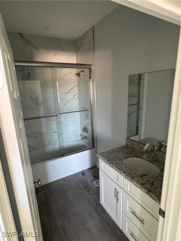 bathroom with hardwood / wood-style floors, vanity, and combined bath / shower with glass door