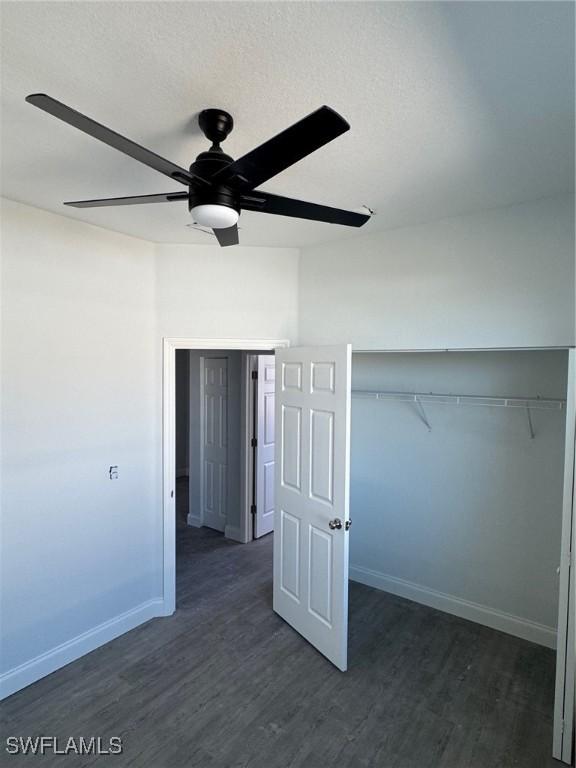 unfurnished bedroom with ceiling fan, dark hardwood / wood-style floors, a textured ceiling, and a closet