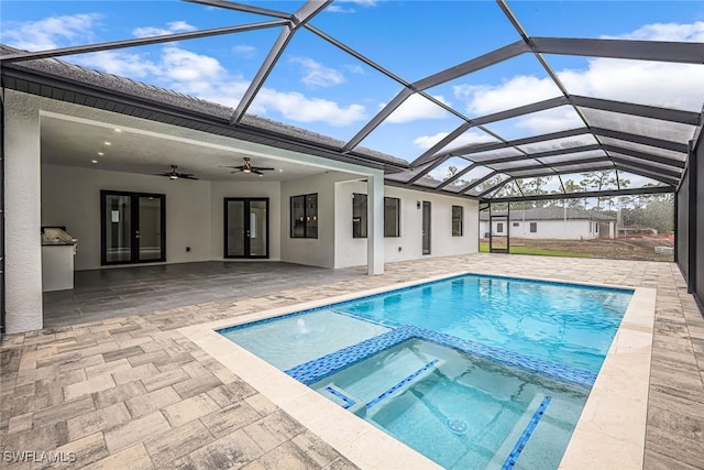 view of pool with ceiling fan, glass enclosure, a patio, and an in ground hot tub