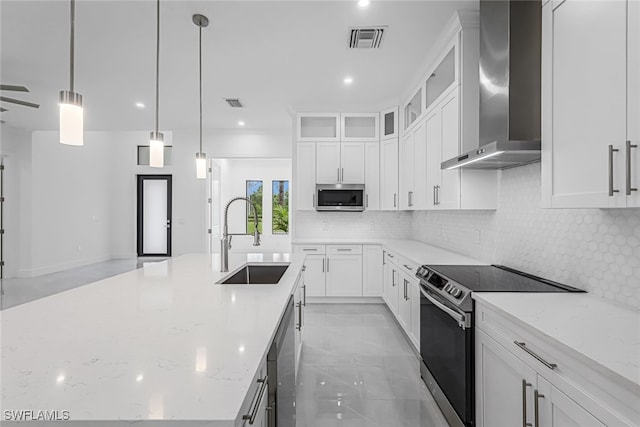 kitchen with backsplash, sink, hanging light fixtures, stainless steel appliances, and wall chimney range hood