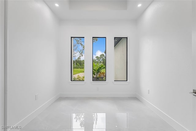 spare room with tile patterned flooring and a raised ceiling