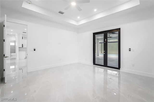 unfurnished room with ceiling fan, a raised ceiling, light tile patterned floors, and french doors