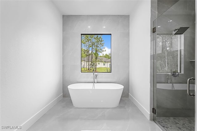 bathroom with tile walls, independent shower and bath, and tile patterned floors