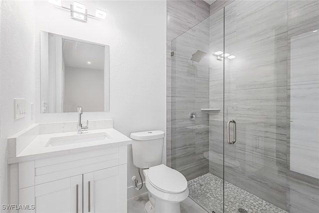 bathroom with toilet, vanity, and a shower with shower door