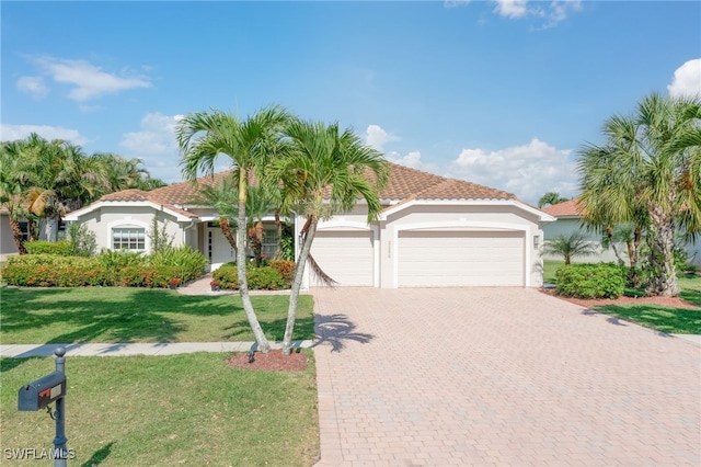 mediterranean / spanish-style house with a garage, a front lawn, decorative driveway, and stucco siding