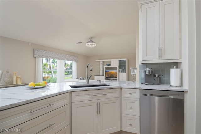 kitchen featuring white cabinetry, a sink, stainless steel dishwasher, and light stone countertops