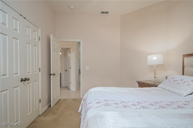 bedroom featuring a closet, visible vents, light carpet, and baseboards