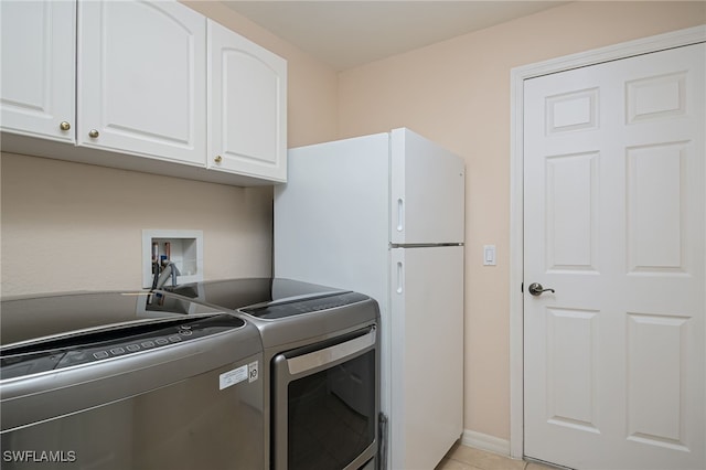 washroom featuring washing machine and dryer, light tile patterned flooring, and cabinets