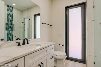 bathroom with walk in shower, vanity, and toilet