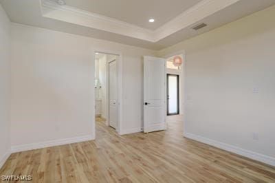 unfurnished bedroom with light hardwood / wood-style flooring and a raised ceiling