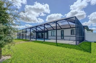 rear view of house with a yard, glass enclosure, and a patio area