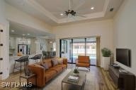 living room featuring ceiling fan, a raised ceiling, and wood-type flooring