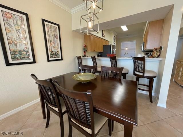 dining room with baseboards, light tile patterned flooring, and crown molding