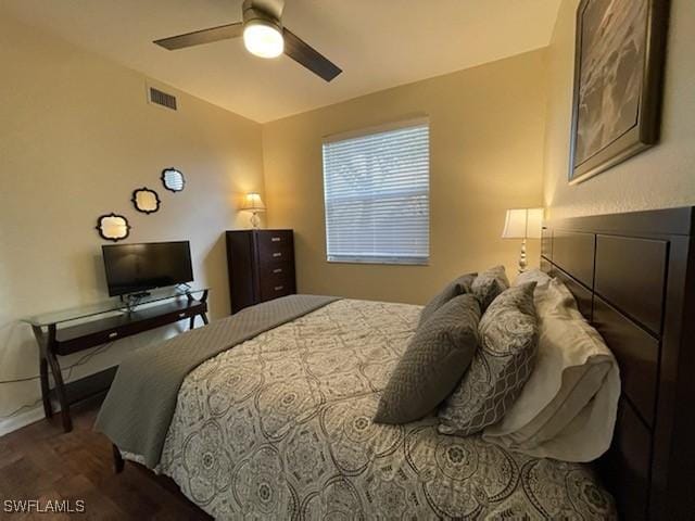 bedroom with ceiling fan, dark wood-type flooring, visible vents, and baseboards