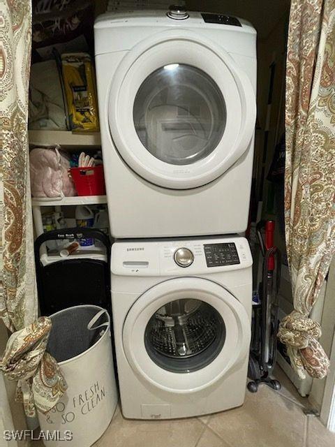 laundry area with stacked washing maching and dryer, light tile patterned floors, and laundry area