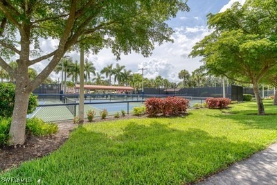 view of sport court with fence and a lawn