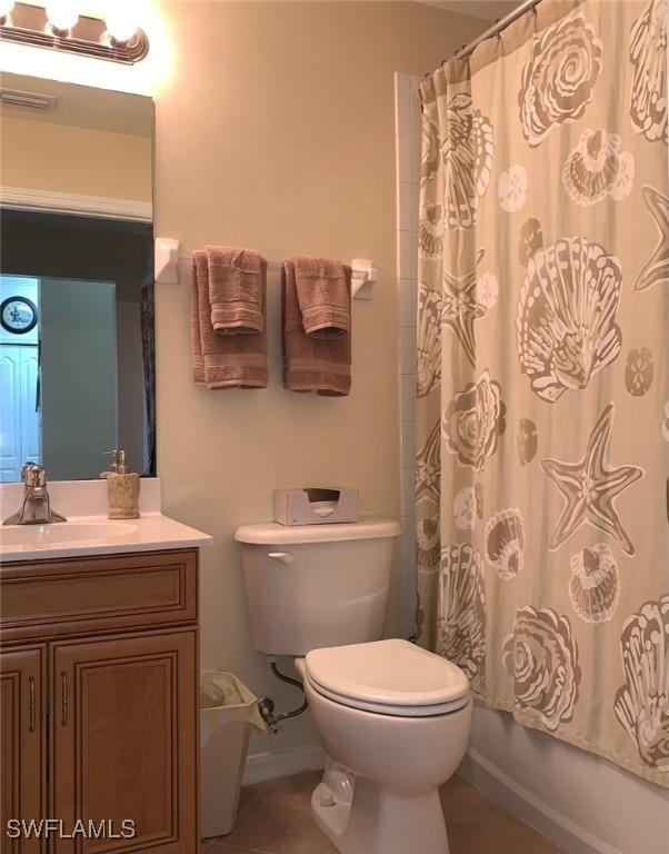 bathroom featuring shower / bathtub combination with curtain, toilet, vanity, tile patterned flooring, and baseboards