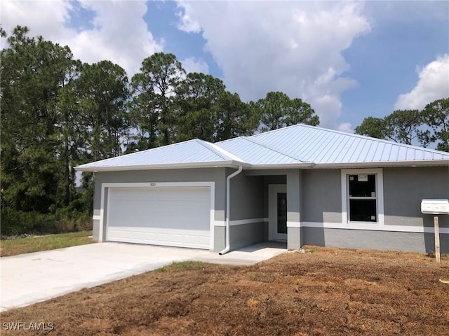 single story home featuring stucco siding, an attached garage, metal roof, and driveway