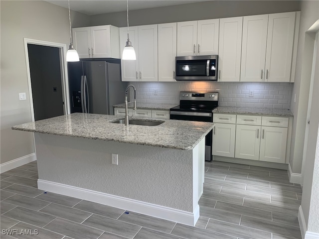 kitchen with sink, decorative backsplash, a kitchen island with sink, and appliances with stainless steel finishes