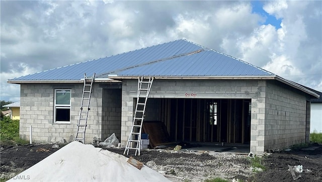 view of front of property with concrete block siding, an attached garage, and metal roof