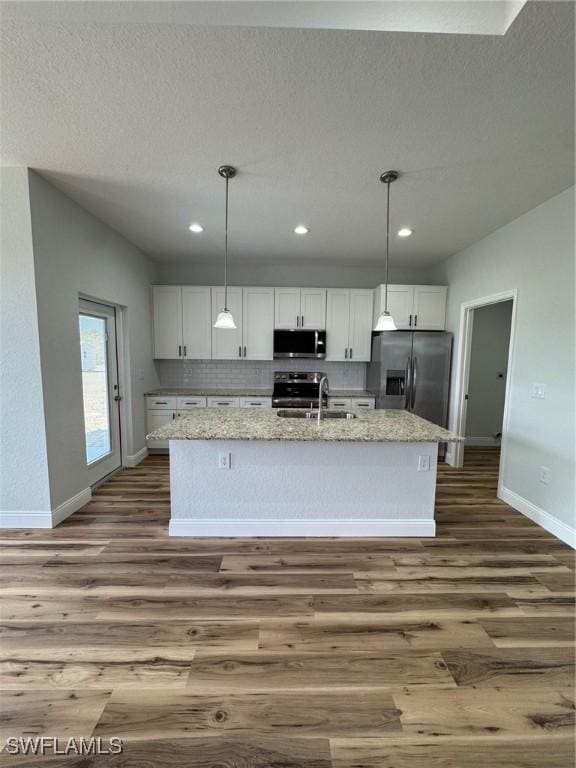 kitchen featuring dark wood-type flooring, stainless steel appliances, white cabinets, and baseboards
