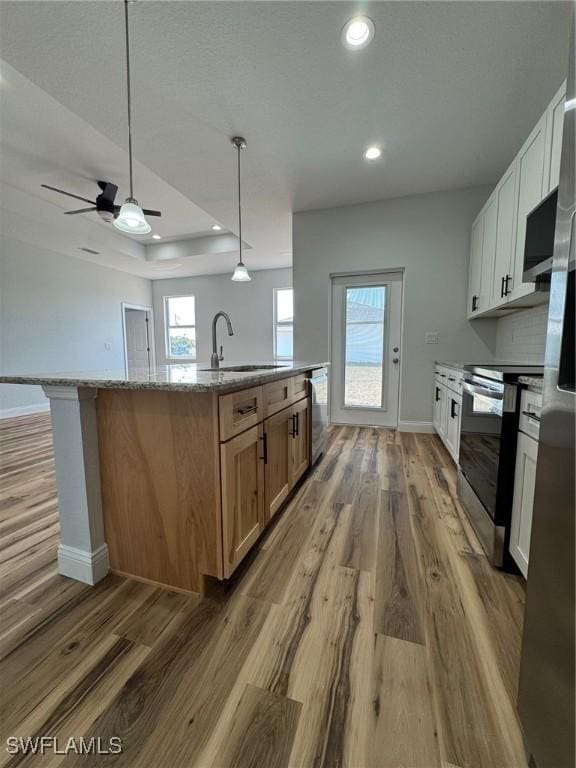 kitchen featuring wood finished floors, a kitchen island with sink, appliances with stainless steel finishes, and a sink