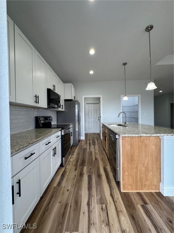 kitchen featuring stainless steel microwave, a sink, black / electric stove, dishwasher, and dark wood finished floors