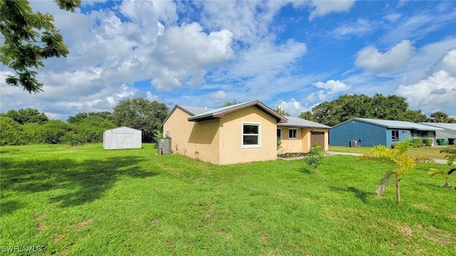 rear view of house with a lawn and a storage unit