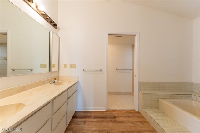 bathroom with hardwood / wood-style flooring, a washtub, lofted ceiling, and vanity