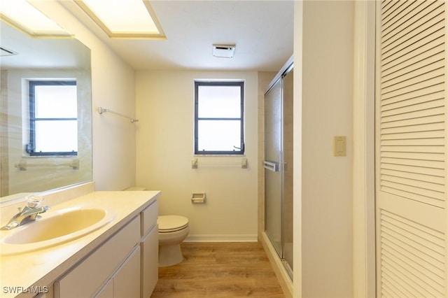 bathroom with a shower with shower door, toilet, wood-type flooring, and vanity