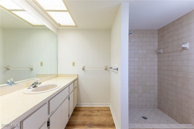 bathroom featuring hardwood / wood-style floors, vanity, and tiled shower