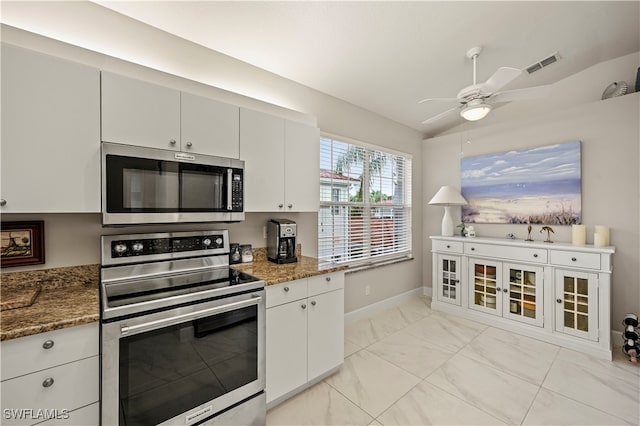 kitchen featuring appliances with stainless steel finishes, white cabinetry, dark stone countertops, vaulted ceiling, and ceiling fan