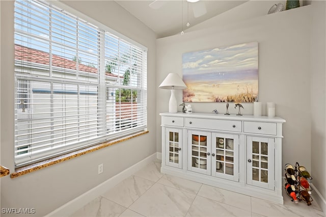 interior space featuring ceiling fan, white cabinetry, and lofted ceiling