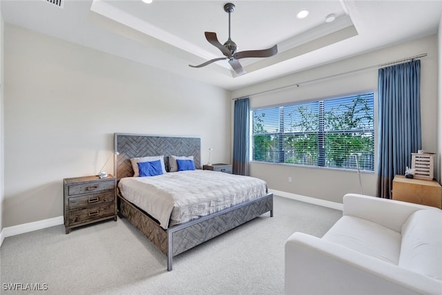 carpeted bedroom featuring ceiling fan, a raised ceiling, and crown molding