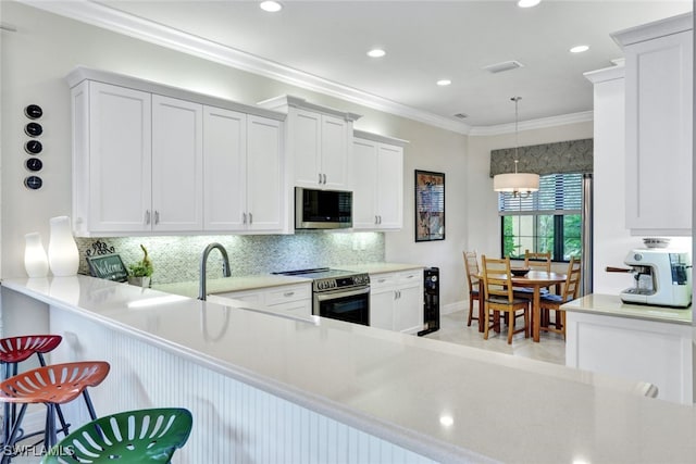 kitchen with a breakfast bar, white cabinets, kitchen peninsula, stainless steel appliances, and crown molding