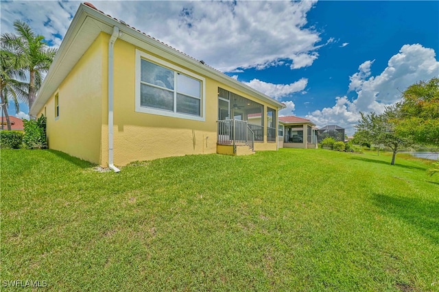 back of house with a yard and a sunroom