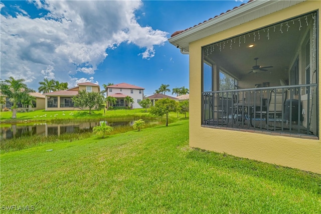 view of yard with ceiling fan and a water view