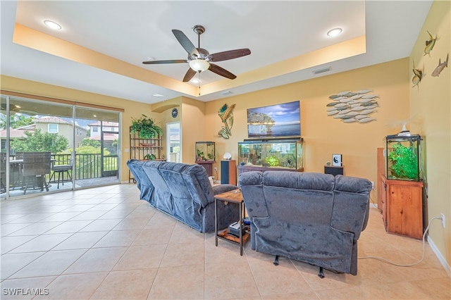 living room featuring light tile patterned flooring, a raised ceiling, and ceiling fan