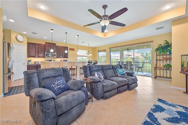 tiled living room with a tray ceiling, ceiling fan, and sink