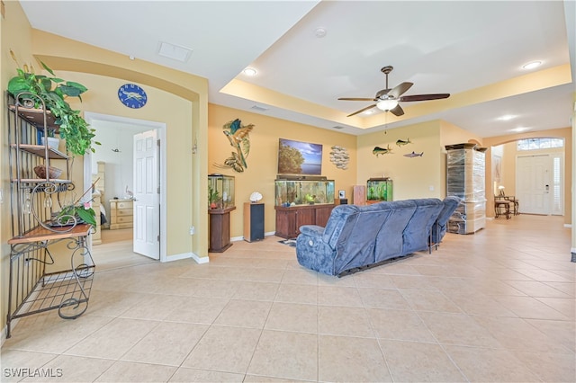 living room featuring ceiling fan, light tile patterned floors, and a tray ceiling