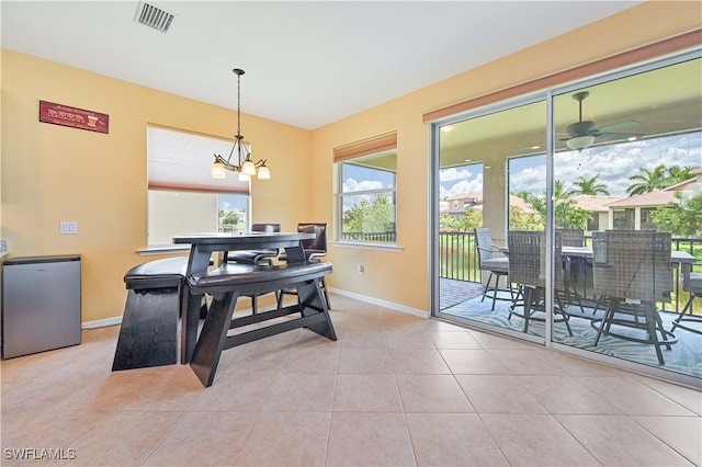 dining space with light tile patterned flooring and ceiling fan with notable chandelier