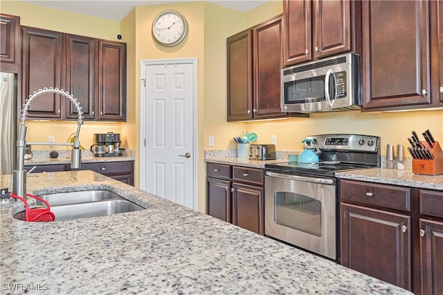 kitchen featuring appliances with stainless steel finishes, light stone counters, and sink