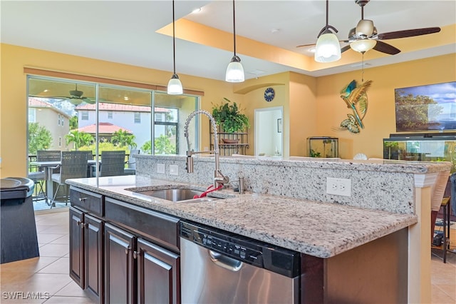 kitchen with light tile patterned flooring, stainless steel dishwasher, sink, and light stone countertops