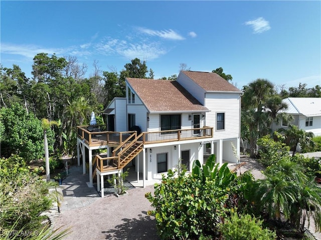 rear view of property featuring roof with shingles, stairway, a patio area, driveway, and a wooden deck