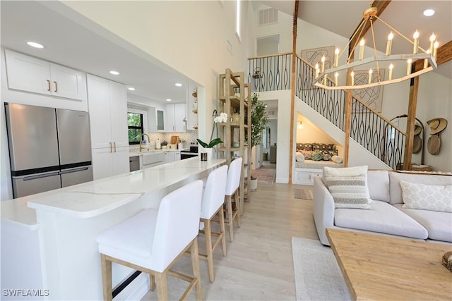 interior space featuring recessed lighting, visible vents, a towering ceiling, light wood-style floors, and stairway