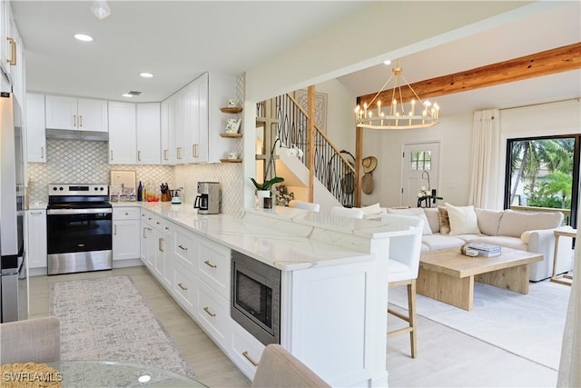 kitchen with tasteful backsplash, appliances with stainless steel finishes, white cabinets, a peninsula, and a kitchen breakfast bar