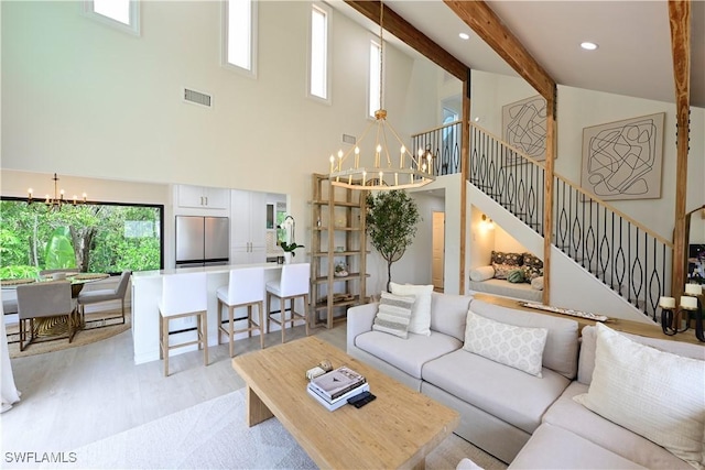 living room featuring visible vents, beamed ceiling, stairs, light wood-type flooring, and a notable chandelier