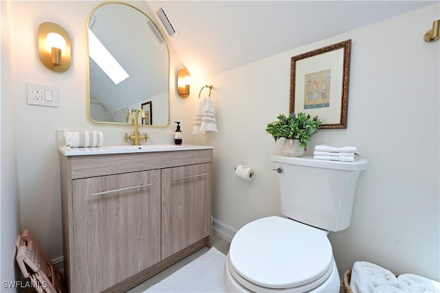 bathroom featuring toilet, baseboards, vaulted ceiling, and vanity