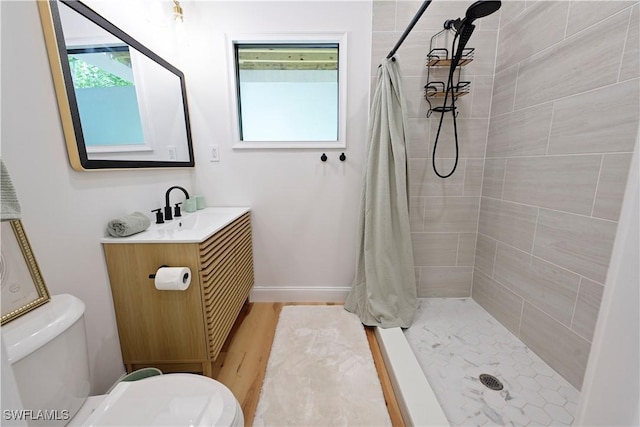 bathroom featuring toilet, a tile shower, and vanity